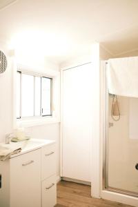 a white bathroom with a shower and a sink at Longford Cottage in Longford +22 photos