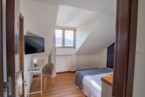 a bedroom with a bed and a desk and a tv at Alda Corcubión in Corcubión