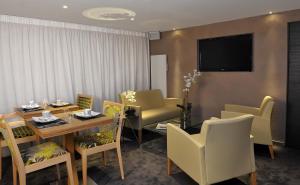 a dining room with a table and chairs and a television at Hotel O2B Aux Berges de Brocéliande in Beignon