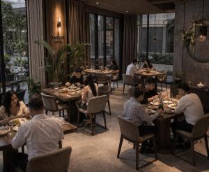 a group of people sitting at tables in a restaurant at Amiron Hotel in Dushanbe