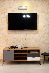 a living room with a television on a wall at Makepe Bungalow Style in Douala