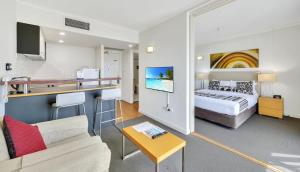 a hotel room with a bed and a kitchen at Cosmo Apartment Hotel in Brisbane