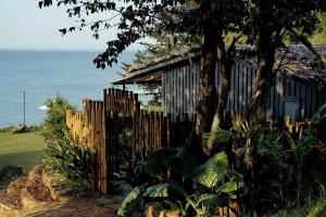 a wooden fence in front of a house next to the ocean at Nomia Garden Retreats - Khu nghỉ dưỡng hồ Trị An in Xóm Ðốt Ðó