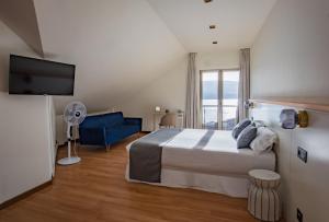 a bedroom with a bed and a tv and a blue couch at Alda Corcubión in Corcubión
