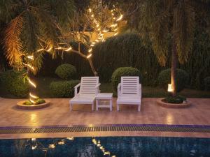 two chairs and a table next to a pool with lights at Fiona Luxury Resort in Gazipur