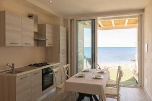 a kitchen with a table and a view of the ocean at Casetta sulla Spiaggia - HelloElba in Capoliveri