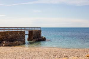 a pier on a beach next to the ocean at Casetta sulla Spiaggia - HelloElba in Capoliveri +2 photos