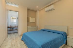 a bedroom with a blue bed and a bathroom at Casetta sulla Spiaggia - HelloElba in Capoliveri