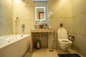 a bathroom with a tub and a toilet and a sink at Hotel Emersion Residency in Pune