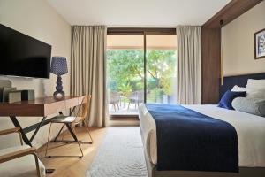 a hotel room with a bed and a desk and a window at La Réserve Esterel in Saint-Raphaël
