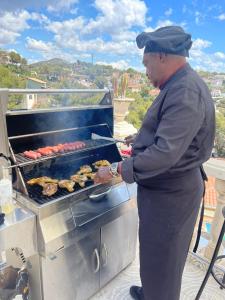 a man cooking food on a grill on a balcony at La Casa de Mima in Cubelles