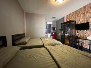 a bedroom with two beds and a television in it at Jinplace Hostel in Ban Khok Chakohan