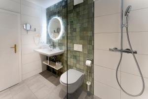 a bathroom with a shower and a toilet and a sink at Seehotel Enzian in Weissensee +105 photos