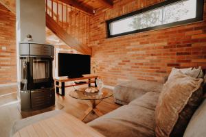 a living room with a couch and a brick wall at Ulinia Zacisze Dom Superior 90m2 - Fala - Mierzeja - Wydma in Ulinia