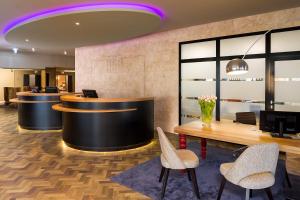 a lobby with a reception desk and chairs and a table at ACHAT Hotel Braunschweig in Braunschweig