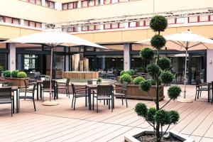 an outdoor patio with tables and chairs and umbrellas at ACHAT Hotel Braunschweig in Braunschweig