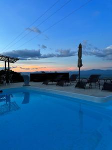 a swimming pool with chairs and a sunset in the background at Pousada No Alto da Serra Conservatória in Conservatória