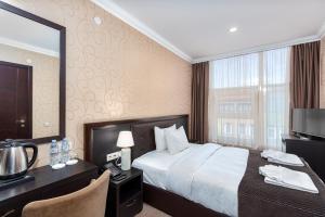 a hotel room with a bed and a desk and a mirror at Kalasi Hotel in Tbilisi City