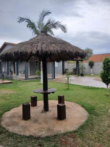 a hut with a table and a palm tree at Paz e tranquilidade in Indaiatuba