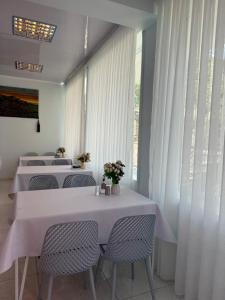 a dining room with white tables and chairs and a window at Гостевой дом Асель in Cholpon-Ata