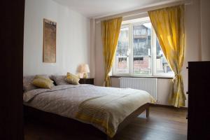 a bedroom with a large bed and two windows at Prahova Valley Apartment in Sinaia