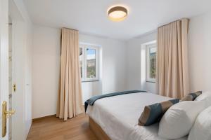 a bedroom with a bed and two windows at Exceptional stone character house Chalet Prazeres in Prazeres