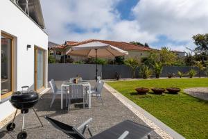 a patio with a table and an umbrella and a grill at Exceptional stone character house Chalet Prazeres in Prazeres