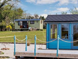 a small blue shack with a house in the background at 1 Bed in Beaworthy oc-77361 in Ashwater