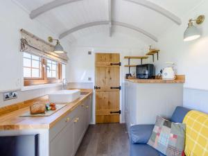 a kitchen with white cabinets and a blue couch at 1 Bed in Beaworthy oc-82834 in Ashwater