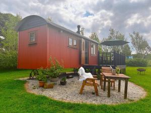 a red tiny house with a picnic table and an umbrella at 1 Bed in Beaworthy oc-82834 in Ashwater