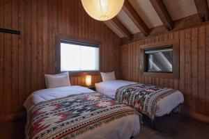 two beds in a room with wooden walls and a window at IZA moriyama in Moriyama +100 photos