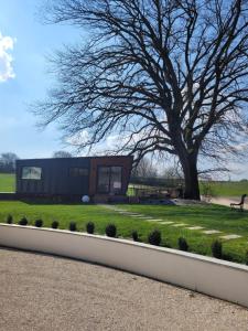 a tiny house in a park with a tree at Au Coin du Chêne in Thaon-les-Vosges