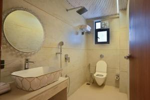 a bathroom with a sink and a toilet and a mirror at Hotel Emersion Residency in Pune