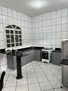 a white tiled kitchen with a table and a stove at Casa nova 2 quartos in Montes Claros