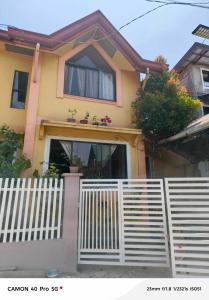 a yellow house with a white fence in front of it at K and E transient loft house in Puerto Princesa City