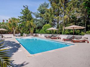 a swimming pool with chairs and umbrellas in a yard at 2 Bed in Minehead oc-90924 in Minehead