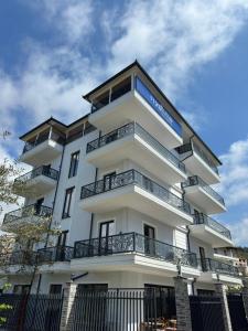 a white building with balconies on the side of it at Ferdinand Residence in Himare