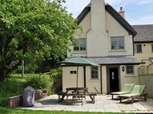 a patio with a table and an umbrella in front of a house at 3 Bed in Axminster oc-bloco in Axminster