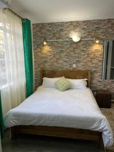 a bed in a room with a brick wall at Kwetuhaven in Kiambu