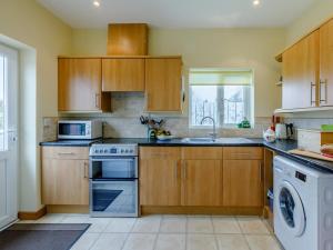 a kitchen with wooden cabinets and a washer and dryer at 2 Bed in Ottery St Mary oc-lambs in Ottery Saint Mary +8 photos