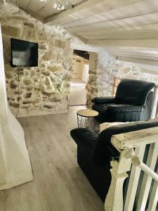 a living room with couches and a stone wall at Aube du Tilleul in Lagorce