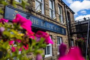 a black sign on the side of a building with pink flowers at The Black Hat in Ilkley +39 photos