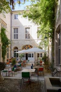 an outdoor patio with tables and chairs and a building at L'Arlatan in Arles