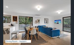 a living room with a blue couch and a table at Maleny Lakeside Retreat l 5BDRM l Firepit l Pets Ok in Maleny