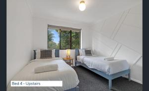a bedroom with two beds and a window at Maleny Lakeside Retreat l 5BDRM l Firepit l Pets Ok in Maleny