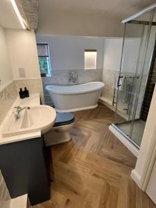 a bathroom with a tub and a toilet and a sink at Habberley Hall Flat in Shrewsbury +26 photos