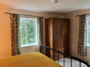 a bedroom with a bed and two windows at Habberley Hall Flat in Shrewsbury