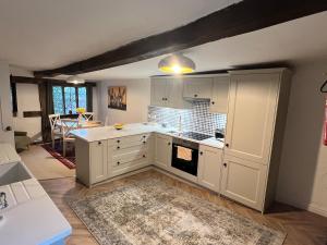 a kitchen with white cabinets and a table with a rug at Habberley Hall Flat in Shrewsbury