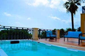 a swimming pool with blue chairs and a palm tree at Villa La Timpa - antica e maestosa villa con jacuzzi privata con una meravigliosa vista sull'Etna e sul mare in Acireale