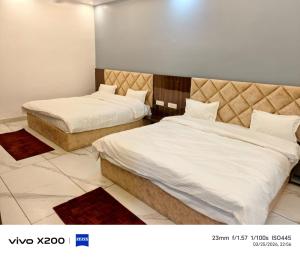 two beds in a hotel room with white sheets at Dev Hotel & Restaurant in Vrindāvan